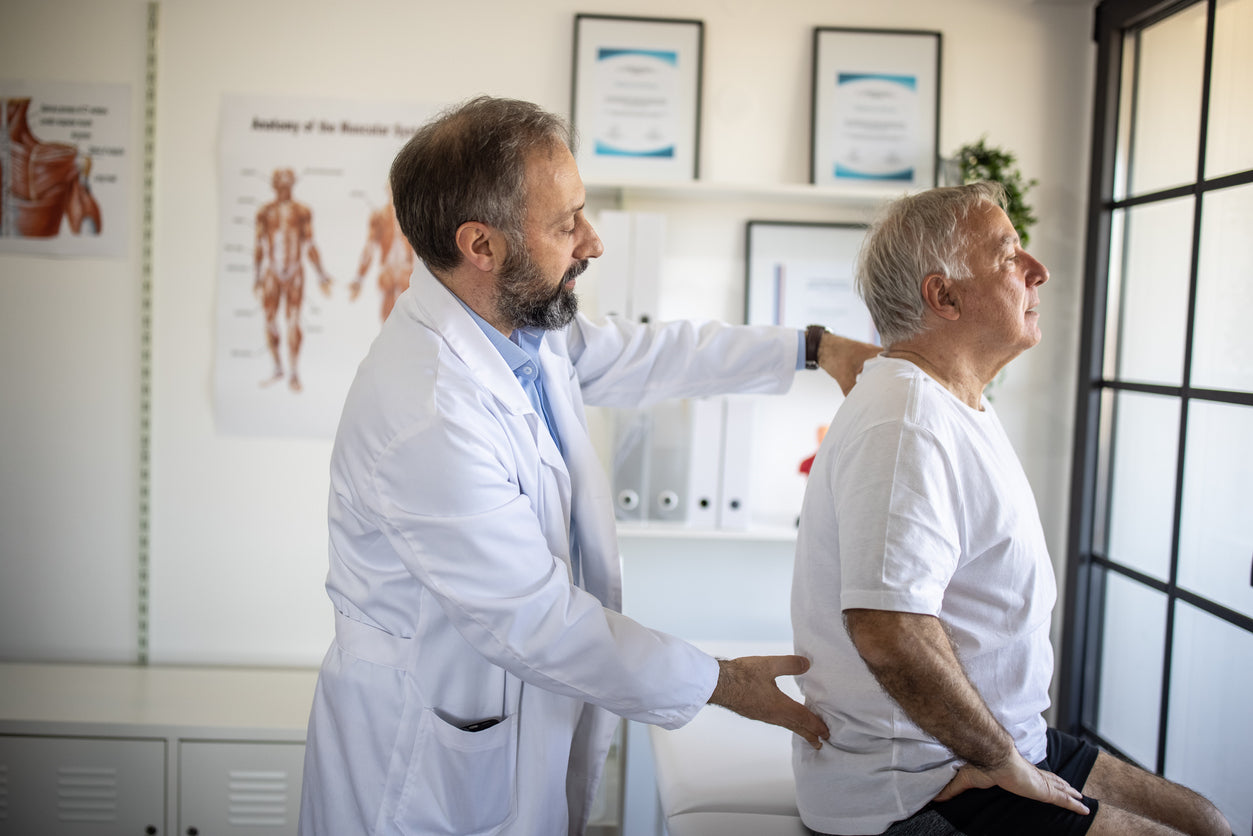 Physical therapist examining senior patient's back injury at doctor's office